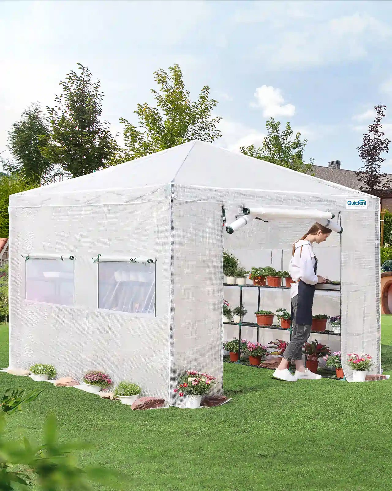 Portable greenhouse with a person inside tending to plants on a sunny day